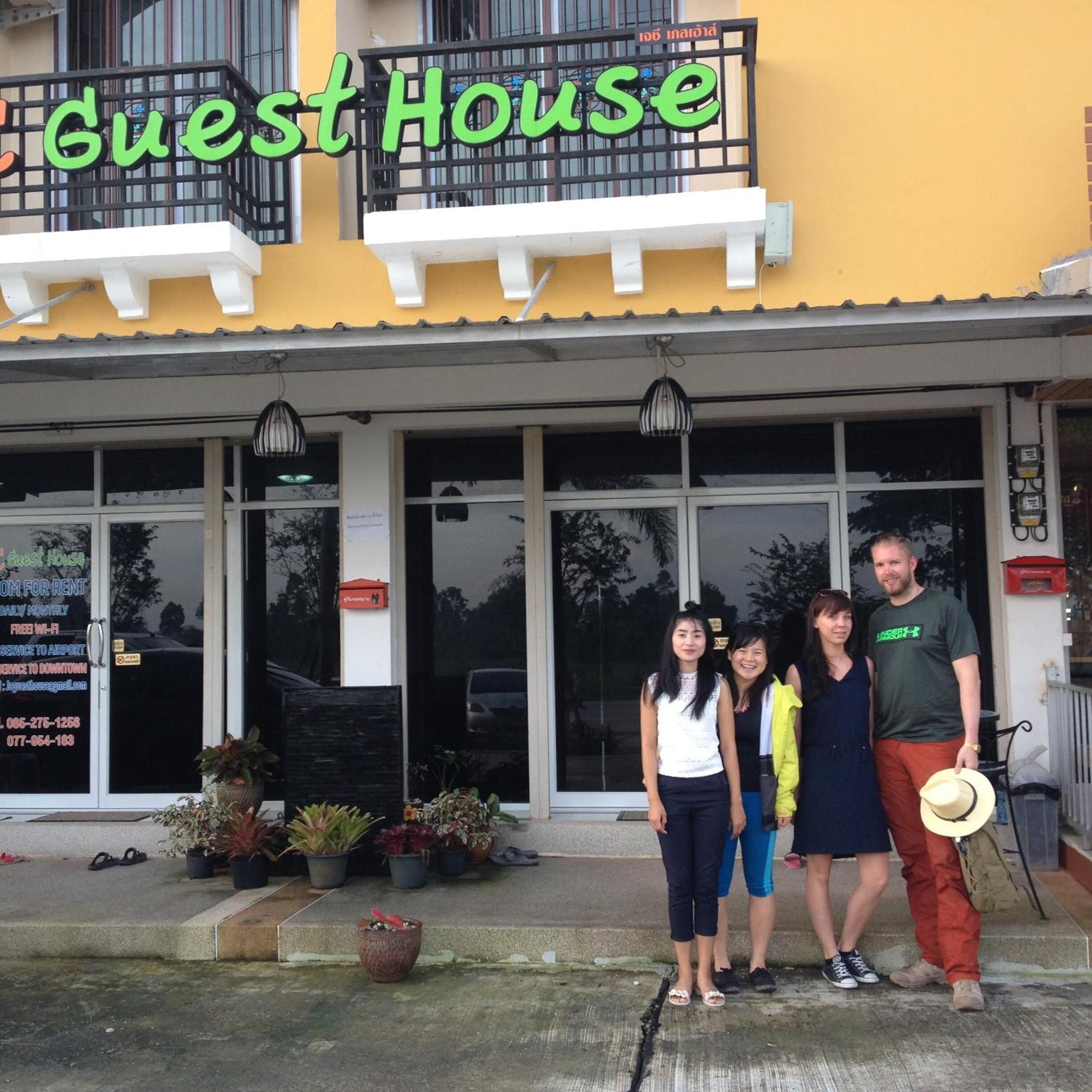 A building with a sign reading "Guest House" and a signboard advertising it as a place for rent.