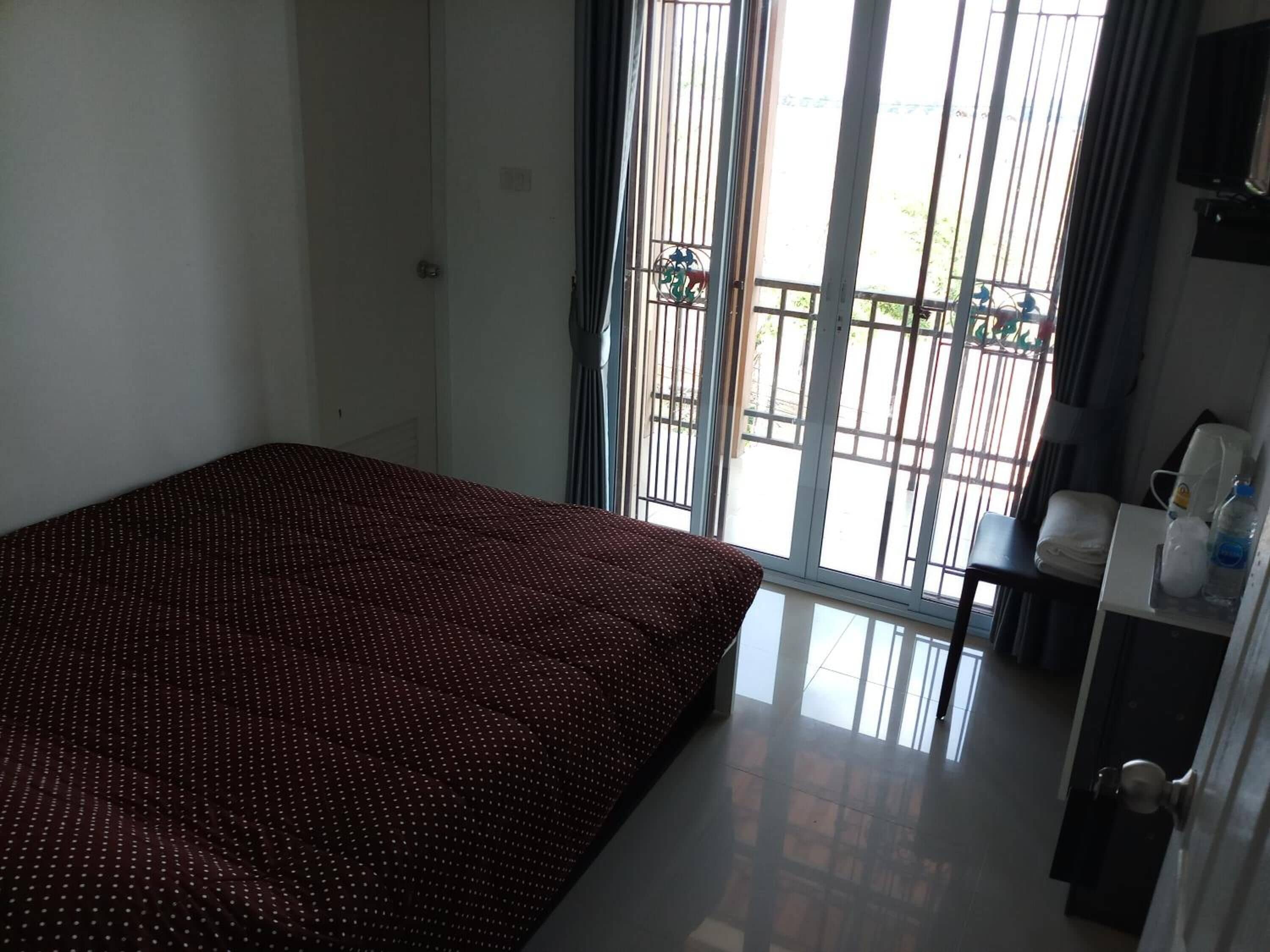 Une chambre d’hôtel avec un lit, un petit bureau, une chaise et une fenêtre donnant sur l’extérieur.