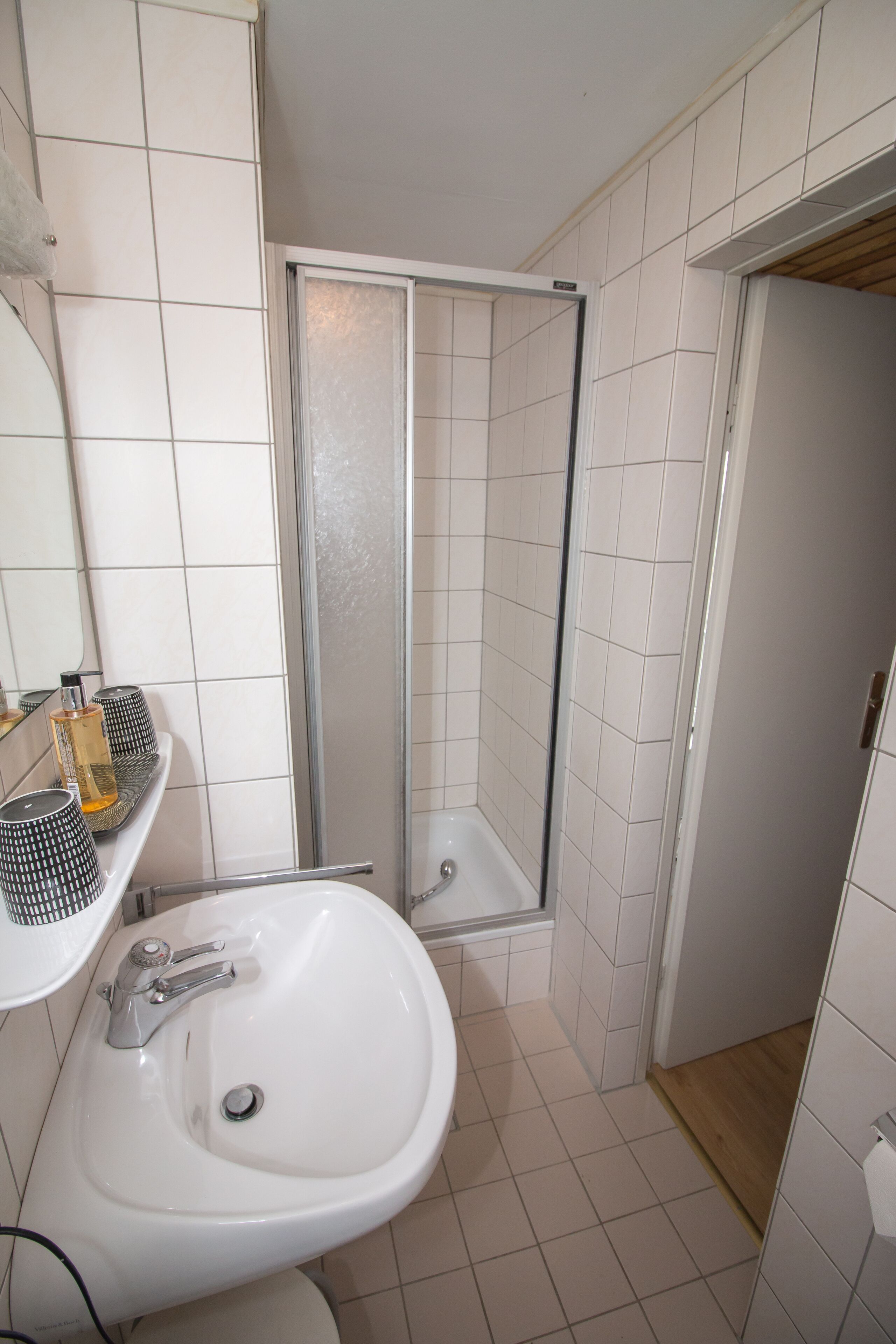 A bathroom with a white sink, a glass shower enclosure, and a mirror above the sink.
