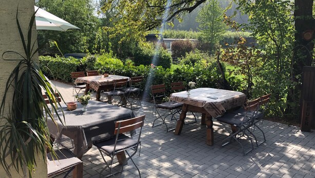 An outdoor patio with tables and chairs, surrounded by greenery and trees. - Landhaus vor Burg Eltz (Wierschem)