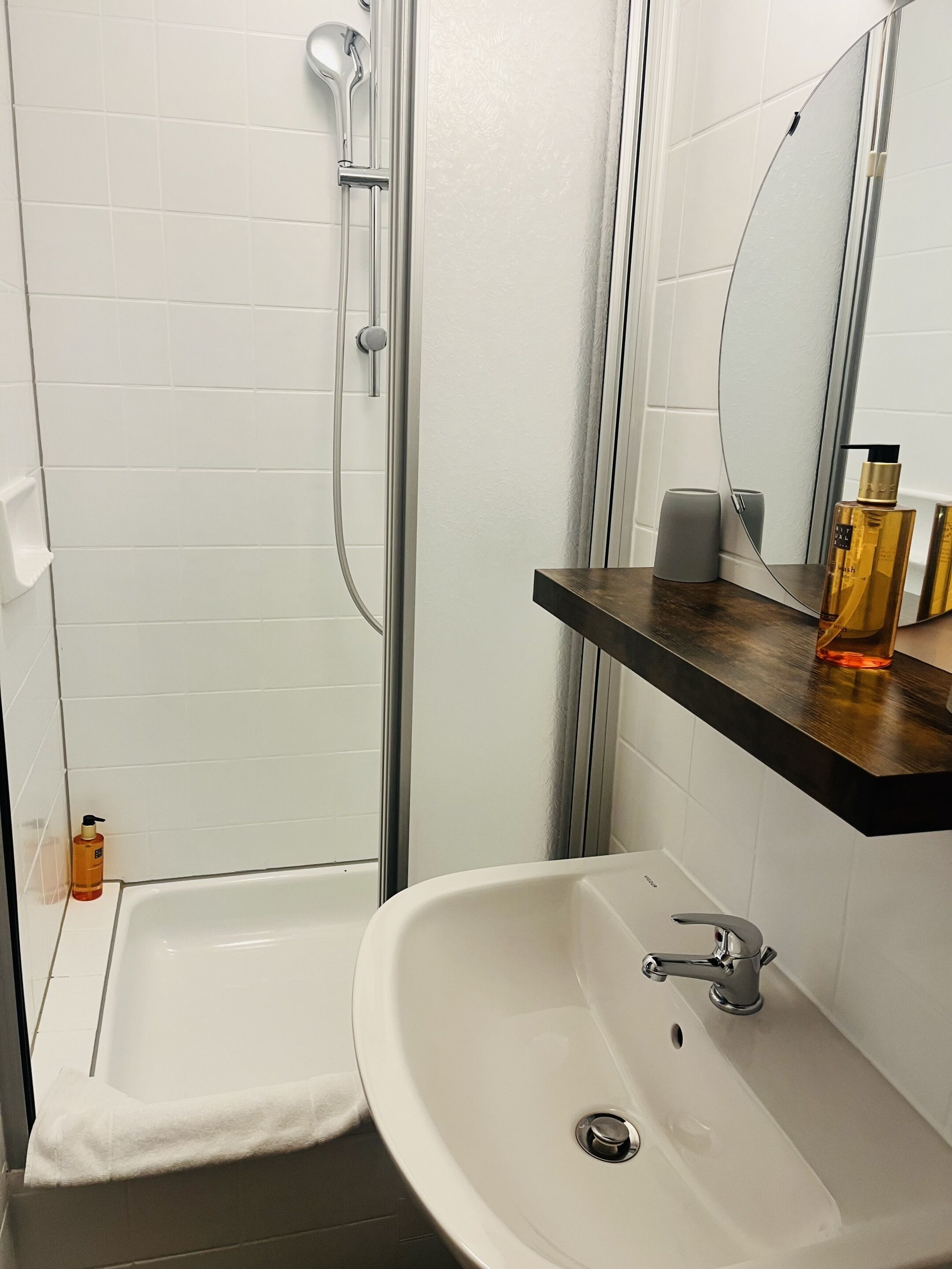 A bathroom with a shower, a sink, and a mirror.