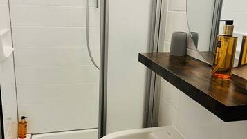 A bathroom with a shower, a sink, and a mirror.