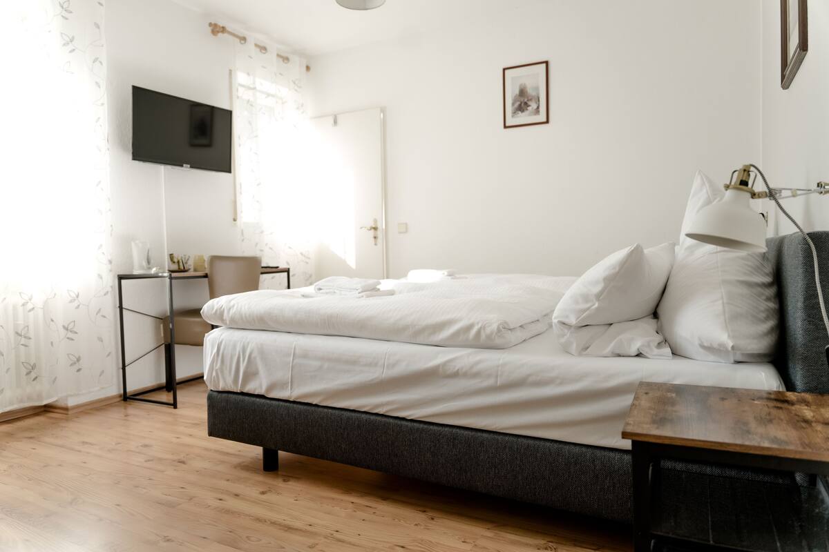 Un dormitorio con cama, escritorio, silla, televisión y lámpara.