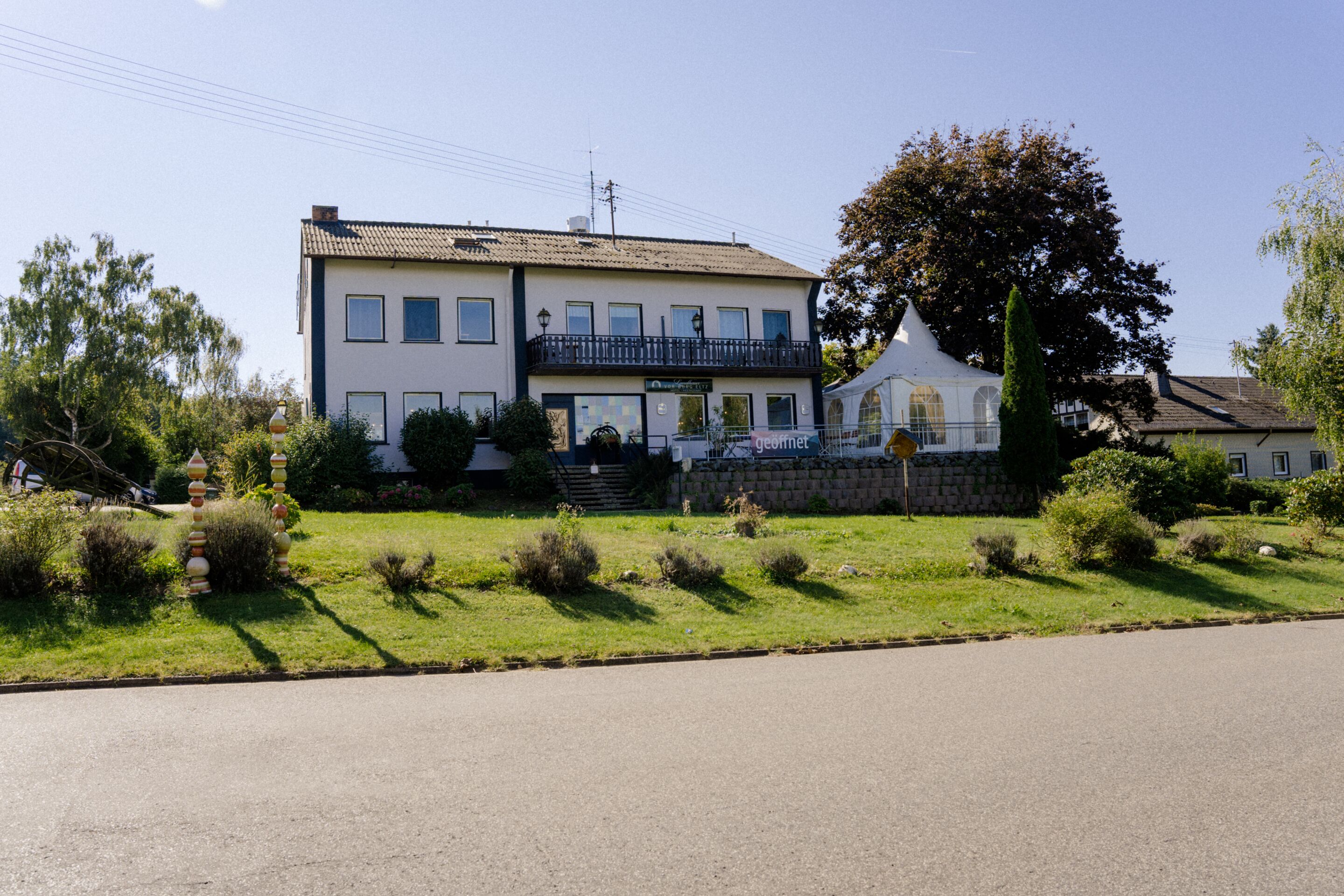 A two-story building with a balcony, a garden, and a clear sky.