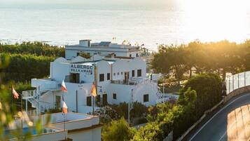 Un edificio blanco con la señalización "ALBERGO VILLA AMARE", un balcón pequeño y vistas al mar.