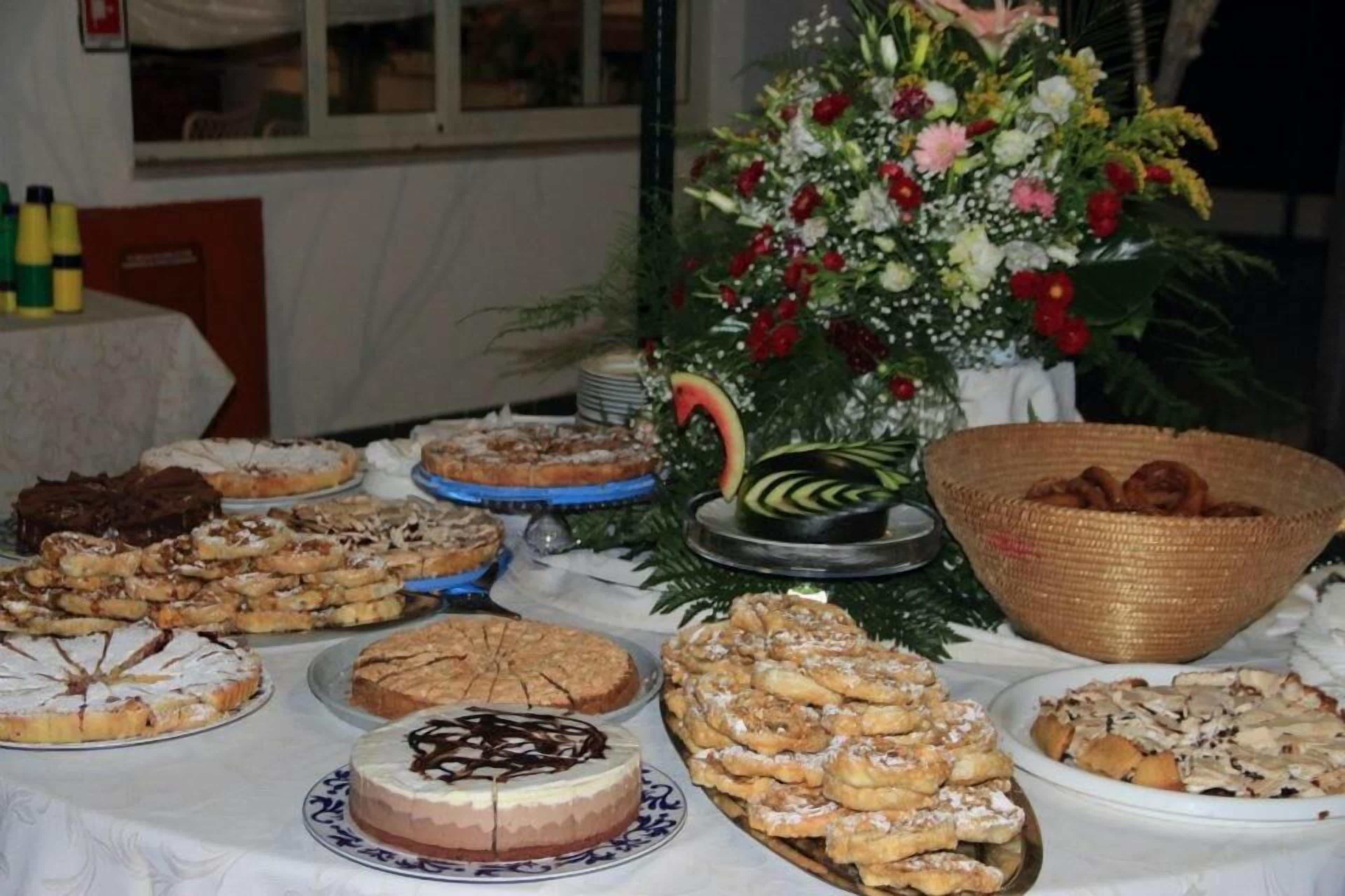 A buffet table with various desserts and a floral arrangement.