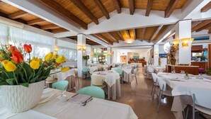 A restaurant with wooden beams, white tables, and chairs.