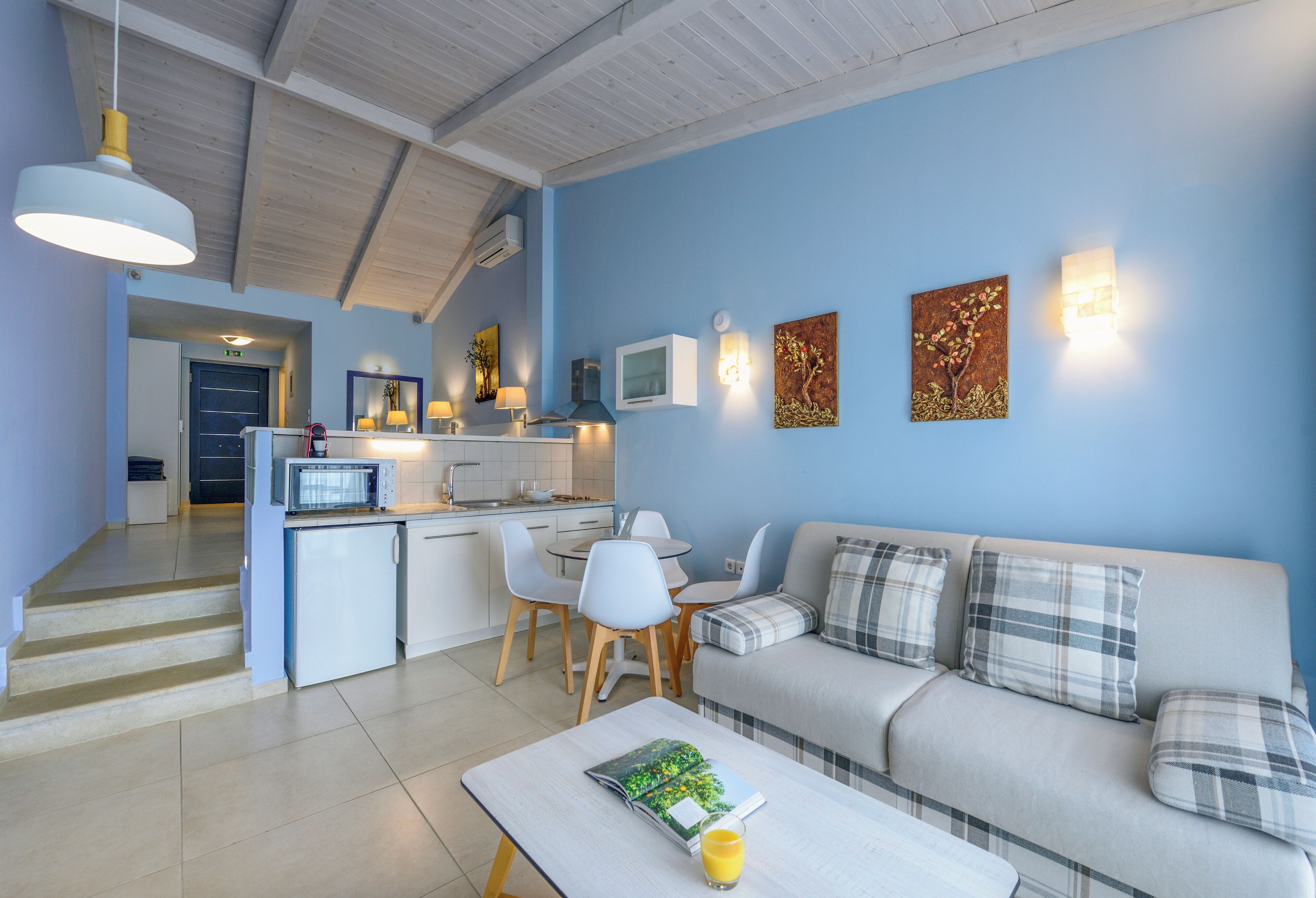 A modern living room with a sofa, coffee table, and a dining area with chairs and a table.
