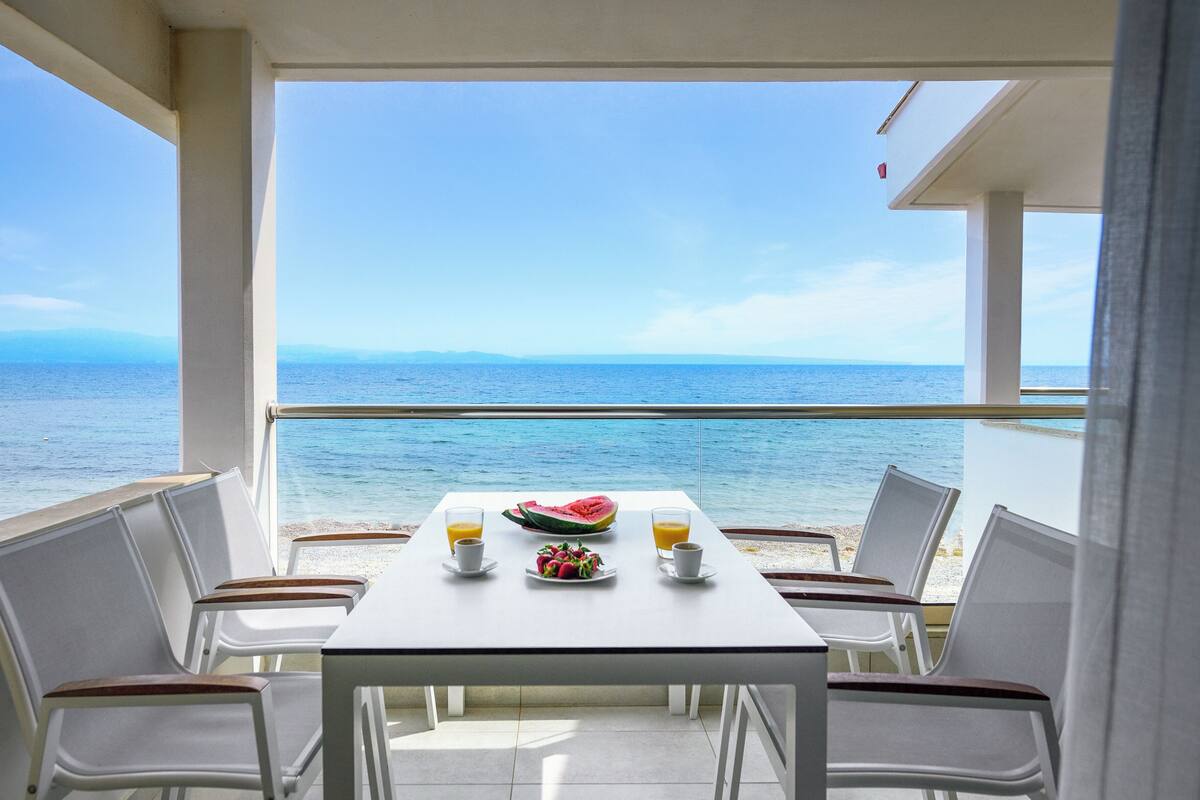 Un balcon avec une table préparée pour le petit-déjeuner, donnant sur la mer.