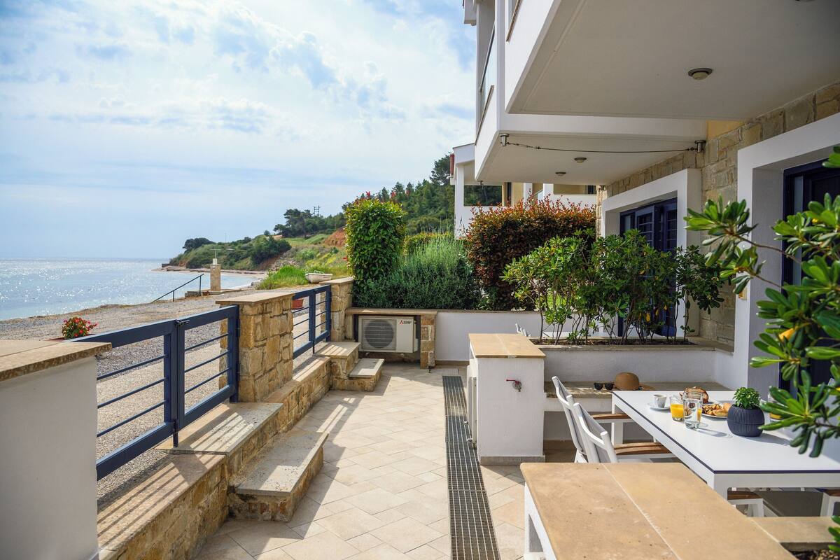 Un balcon avec vue sur la mer, une table avec des sièges pour l’extérieur et un petit espace jardin.