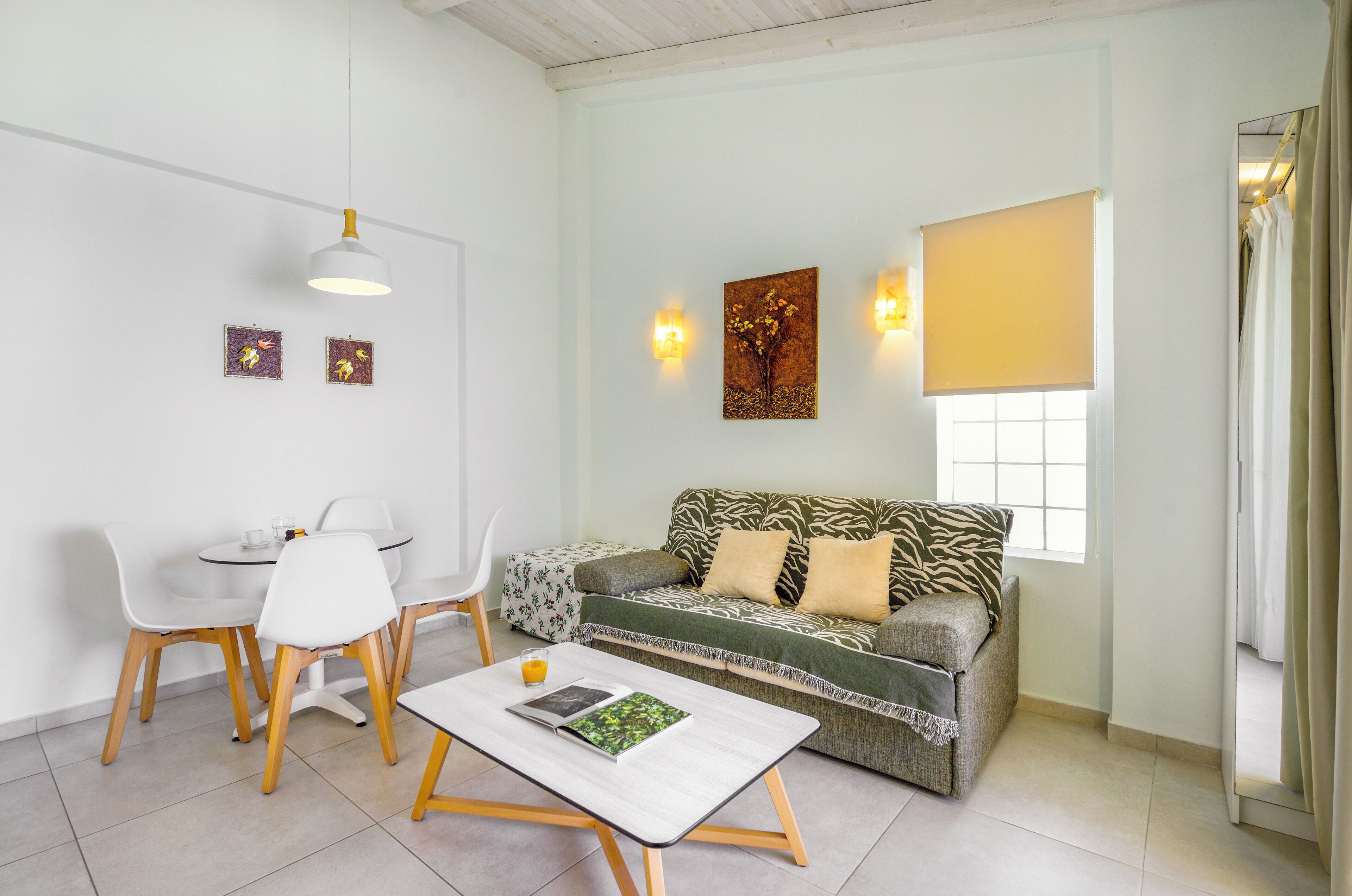 A modern living room with a sofa, a dining table with chairs, a coffee table, and artwork on the walls.