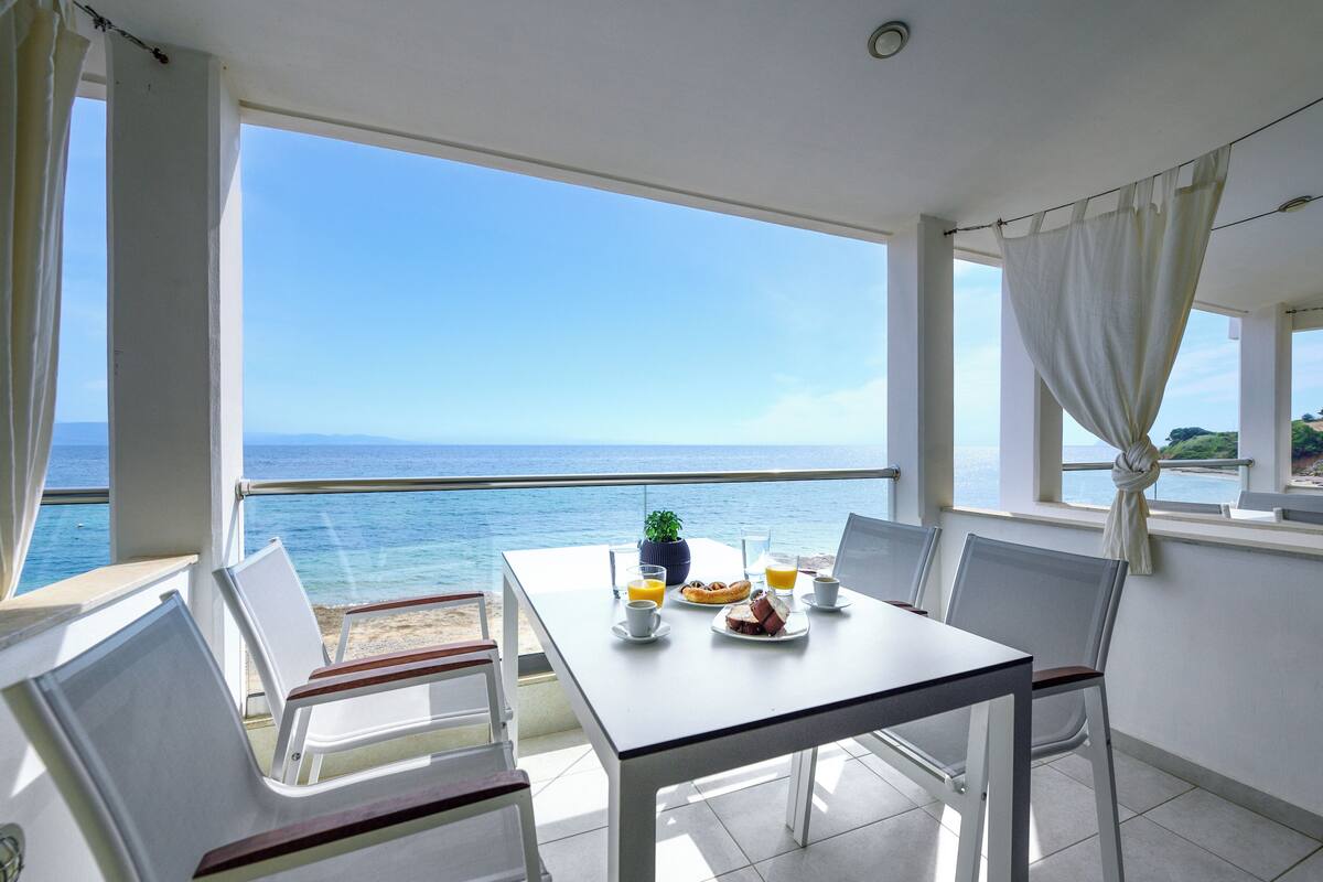 Un balcon avec une table préparée pour le petit-déjeuner, donnant sur la mer.