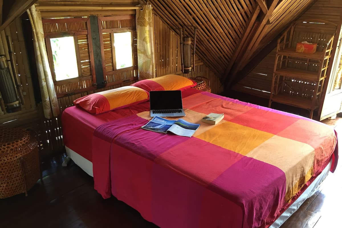 Une chambre avec un lit, un ordinateur portable et un magazine posé sur le lit.