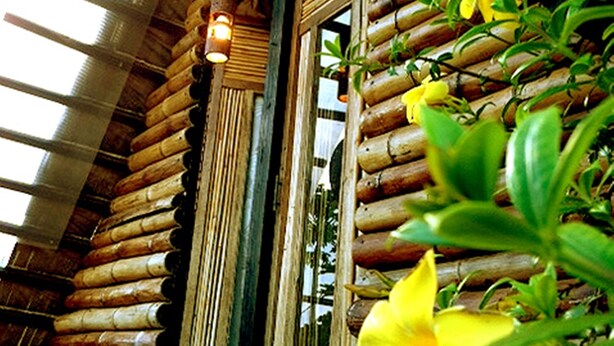 Een knus blokhutachtig huis met een grote houten deur en een hanglamp.