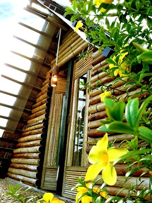 A rustic log cabin with a large wooden door and a hanging light fixture. - The Village House (Puerto Princesa)