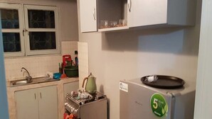 A compact kitchen with a refrigerator, stove, and cabinets. - Résidence Petite Villa (Abidjan)