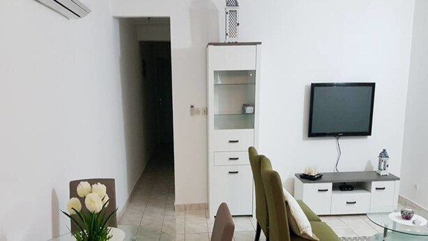 A modern living room with a glass dining table, a sofa, a TV, and a cabinet. - Résidence Petite Villa (Abidjan)