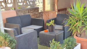 A patio area with wicker furniture, potted plants, and a small table. - Guest House Brezza Marina (Fiumicino)