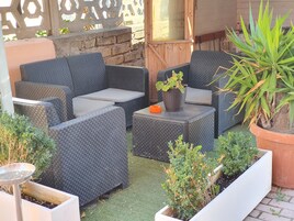 Un'area patio con mobili in vimini, piante in vaso e un tavolino.