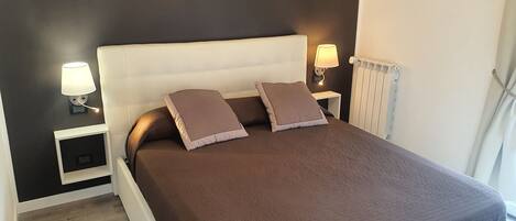 A neatly made bed with a brown quilt, two pillows, and two bedside lamps.