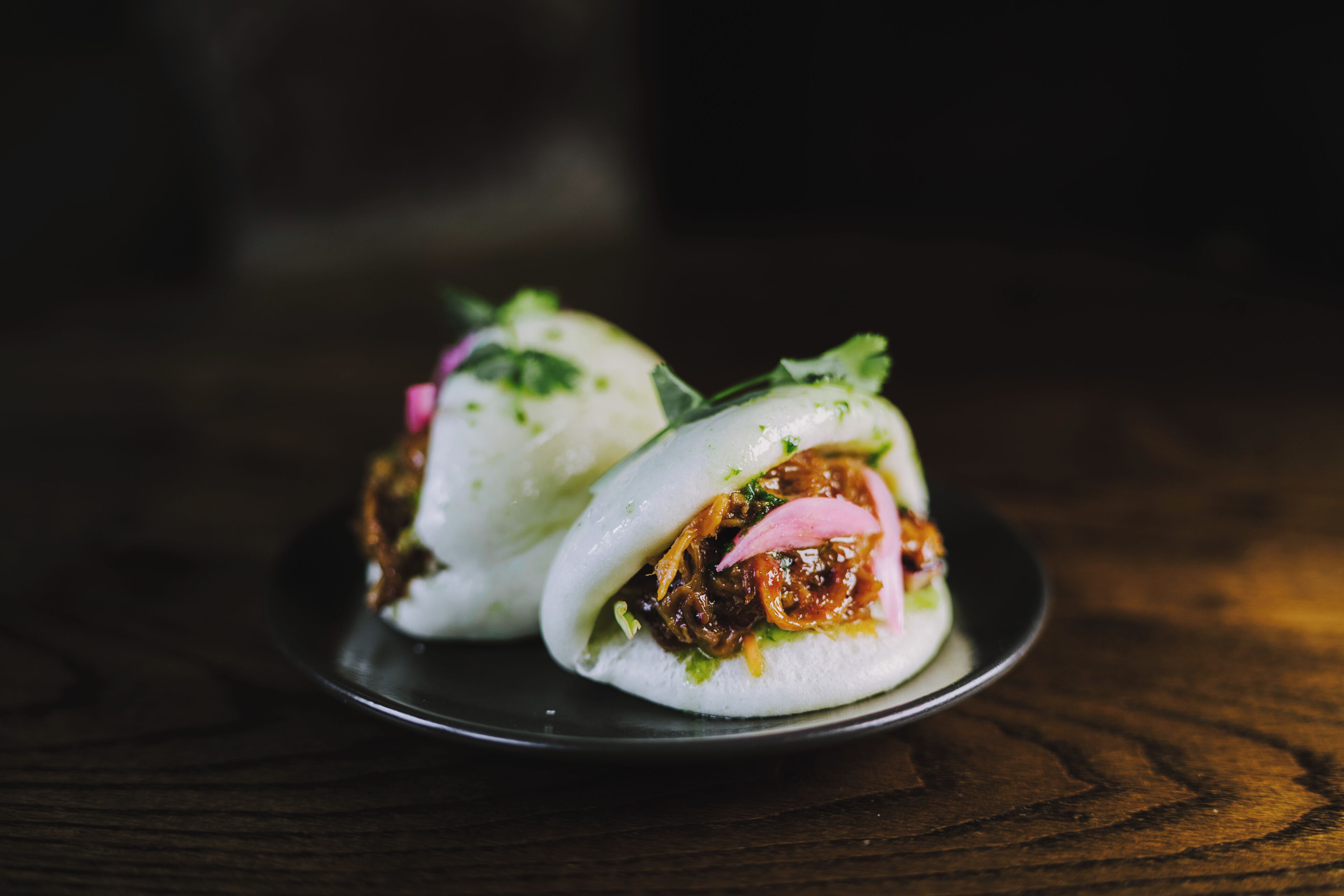 Two white dumplings on a dark plate.