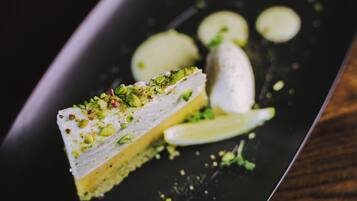 Una porción de postre en capas con pistachos sobre un plato oscuro.