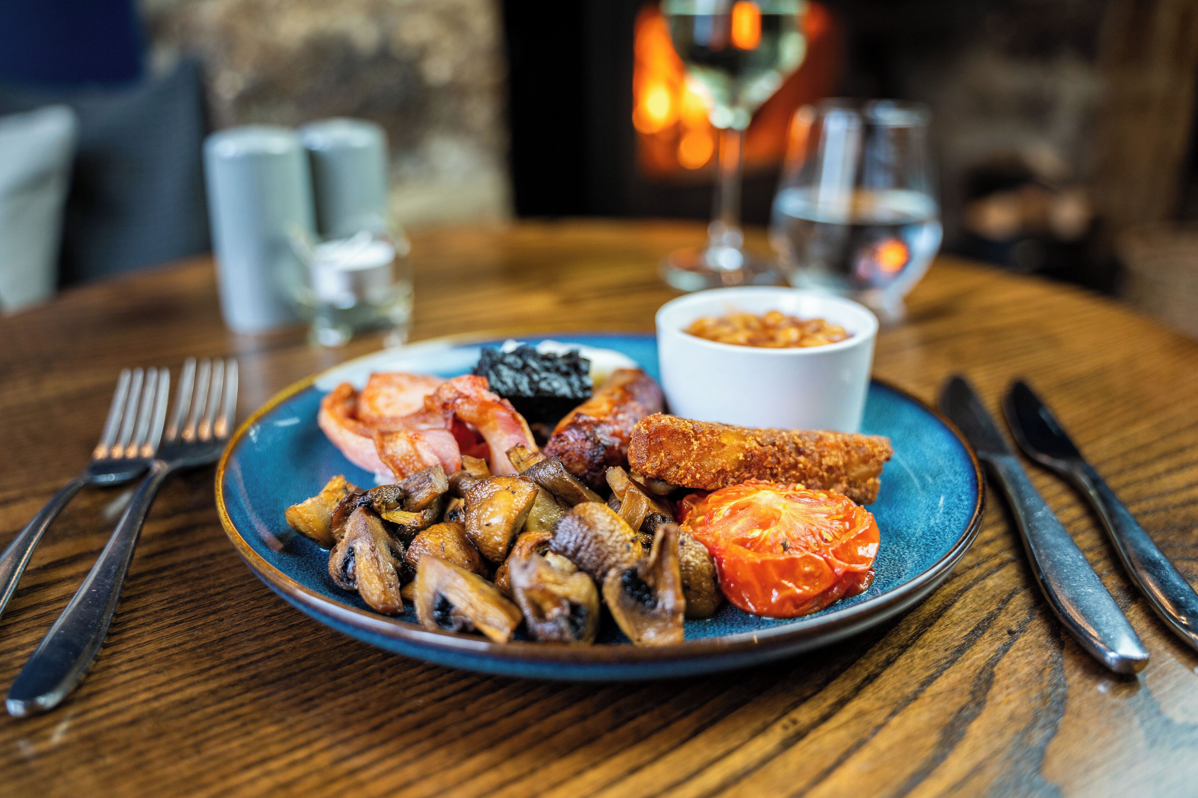 Une assiette de nourriture contenant des champignons, des tomates et de la viande, posée sur une table en bois.