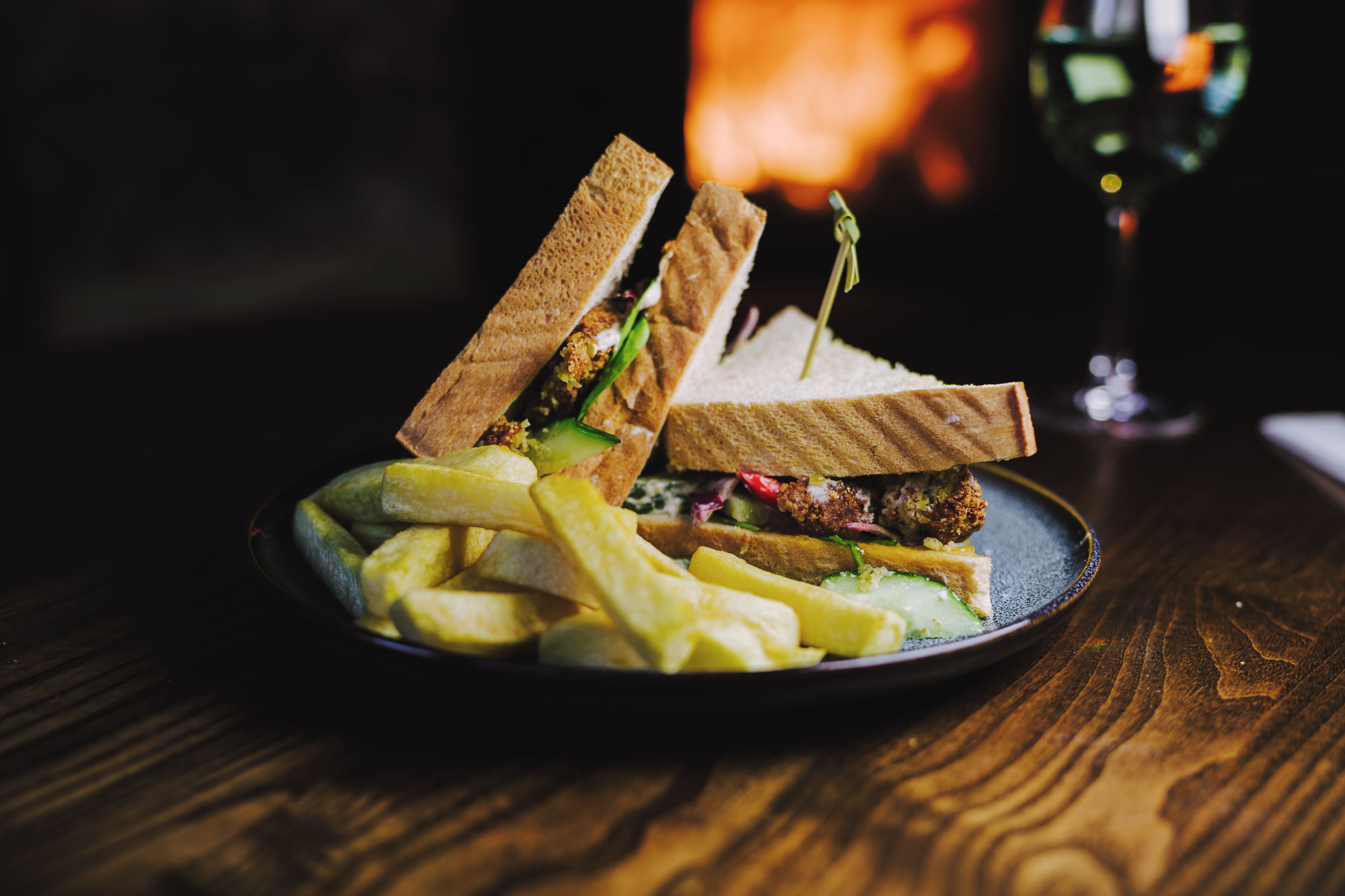 A plate with a sandwich and fries on a wooden table.
