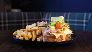 Un plato con un sándwich y papas fritas sobre una mesa de madera oscura.