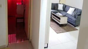 A living room with a grey sofa, white coffee table, and a red curtain in the background. - Résidence Lumière 3 (Abidjan)