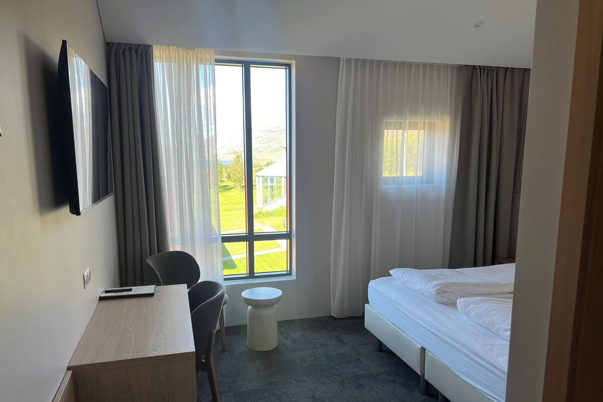 Une chambre d’hôtel comprenant un lit, un bureau, une chaise, une petite table et un téléviseur.
