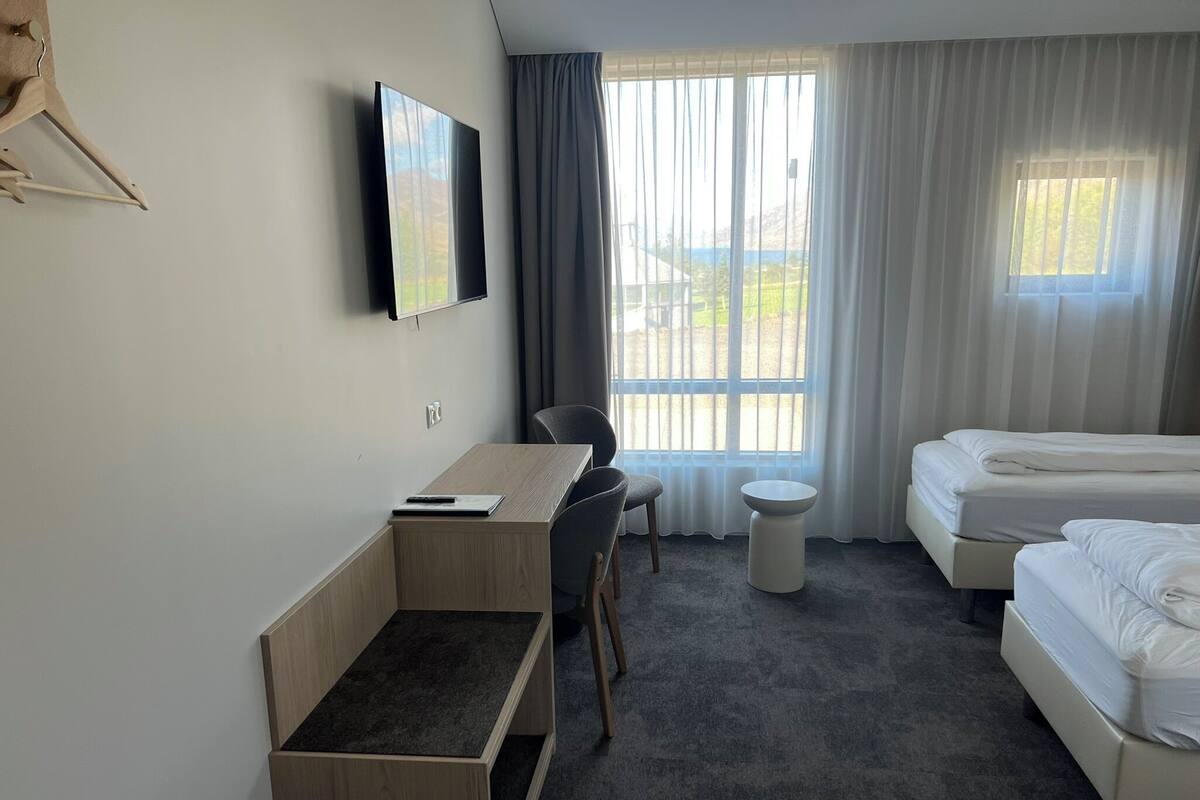 Une chambre d’hôtel équipée d’un bureau, d’une chaise, d’un lit et d’un téléviseur fixé au mur.