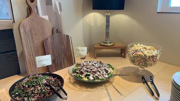 A dining table with various dishes, a lamp, and a wooden cutting board with labels.
