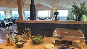 A buffet counter with a variety of food items, condiments, and a grill station. - Hotel Natur  (Akureyri)