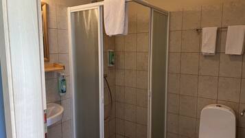Un baño con cabina de ducha, inodoro y lavamanos.