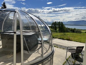 A transparent dome structure with a table and chair inside, overlooking a scenic landscape with a lake and mountains. - Hotel Natur  (Akureyri)