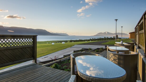 A deck with outdoor seating, a view of the sea, and a mountainous landscape in the background. - Hotel Natur  (Akureyri)