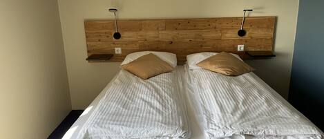 A double bed with two pillows, a wooden headboard, and bedside tables.