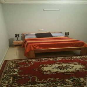 A bedroom with a bed, nightstands, and a patterned rug.