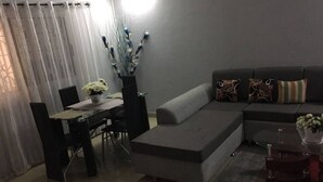 A modern living room with a grey sofa, a dining table with chairs, and a decorative vase with flowers. - Residence Vanessa (Abidjan)