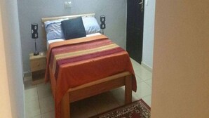 A bedroom with a bed, bedside tables, and a rug. - Residence Vanessa (Abidjan)