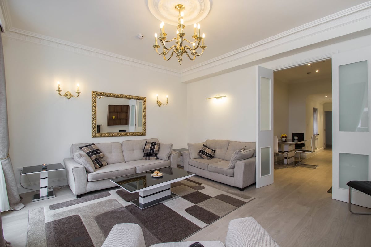 A modern living room with two sofas, a coffee table, and a chandelier.