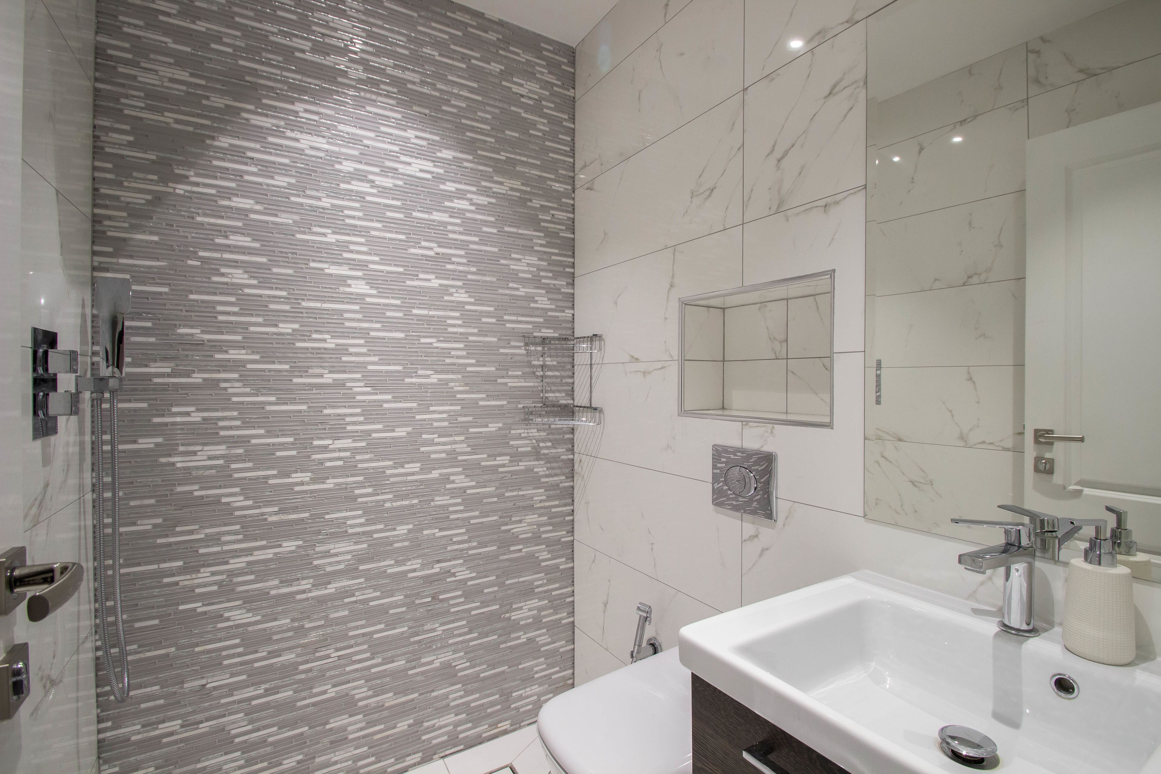 Un baño moderno con ducha, lavamanos y espejo.