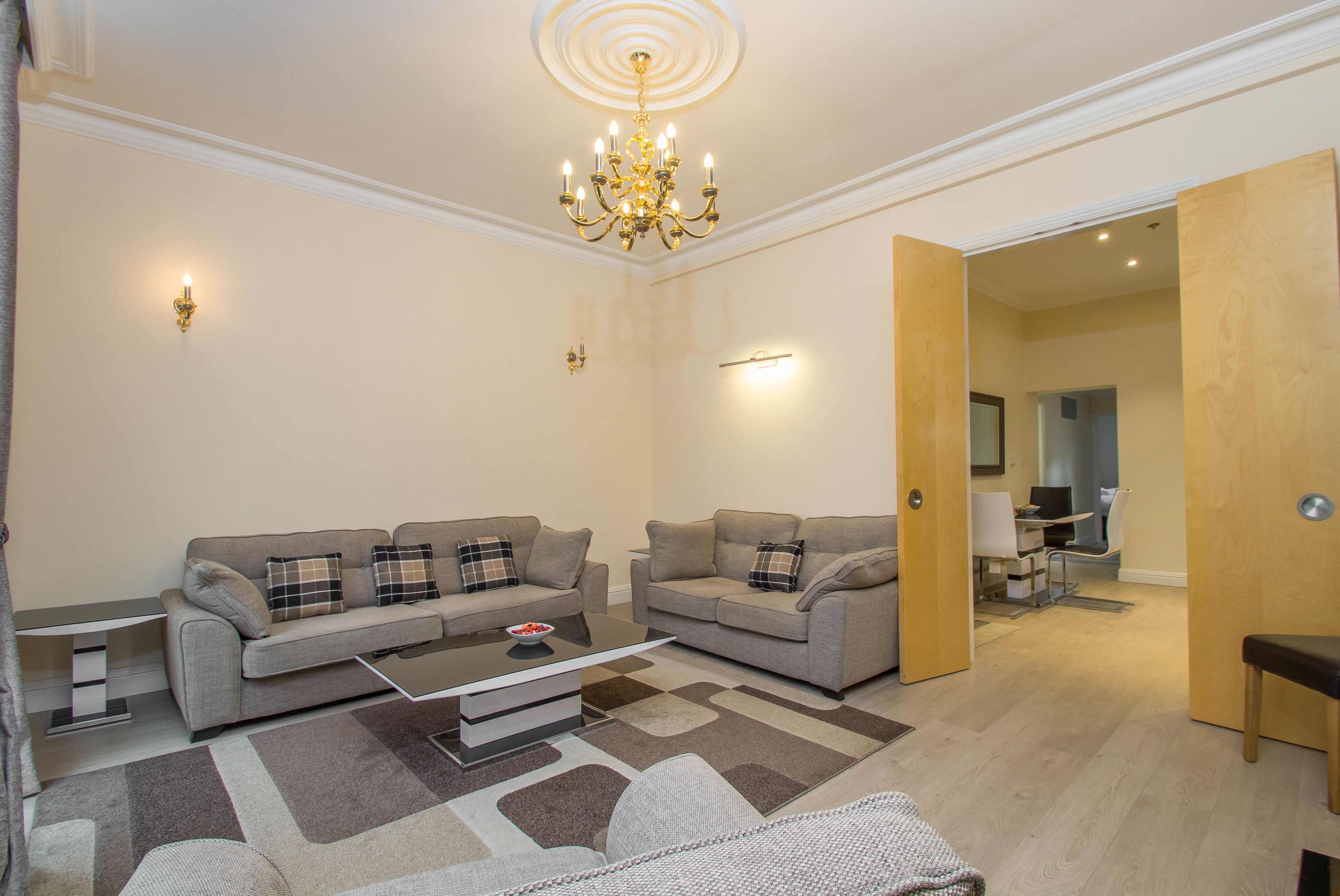 A modern living room with two sofas, a coffee table, and a chandelier.