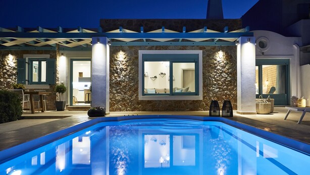 Un área de piscina moderna con fachada de piedra, grandes ventanales y un porche cubierto.