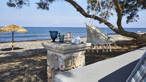 Escena de playa con una mesa, una hamaca y un paraguas de paja.