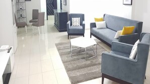 A modern living room with a grey sofa, a coffee table, and a staircase. - Résidence Villa Blanche (Abidjan)