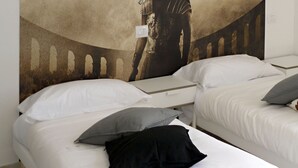 A hotel room with two beds, each with white bedding and pillows. A large poster on the wall reads "GLADIATOR" and features a historical figure. - 5 Rooms (Civitavecchia)