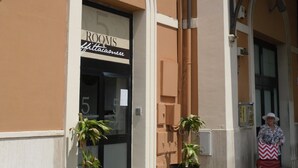 A building with a sign reading "ROOMS" and a potted plant in front. - 5 Rooms (Civitavecchia)