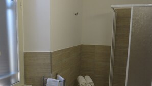 A bathroom with a toilet, a sink, a towel rack, and a shower area. - 5 Rooms (Civitavecchia)